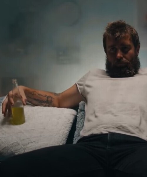 Пьяный мужчина с бутылкой сидит на диване